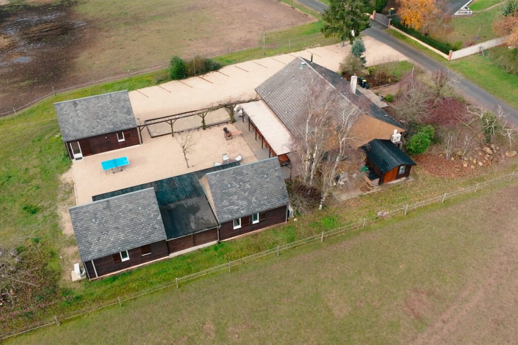 Vue aérienne du gîte Ranch de Sologne avec cour intérieure, bâtiments en bois et terrain verdoyant en pleine nature.