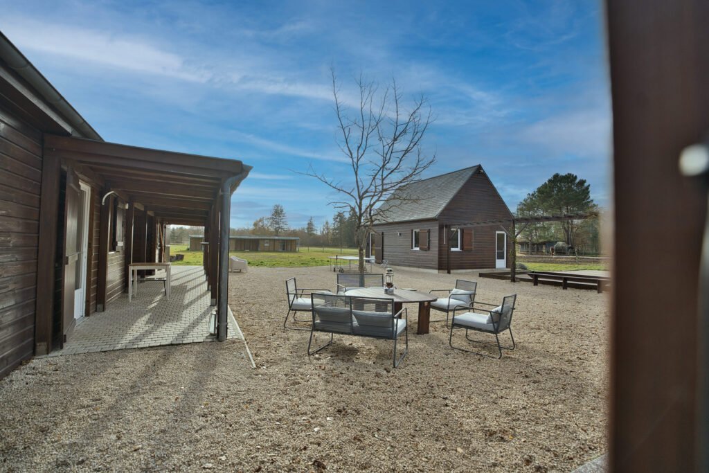 Vue extérieure du gîte Ranch de Sologne avec terrasse, espace détente et salle de jeux visible au fond.