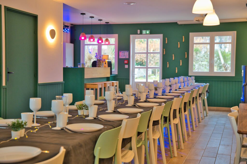Grande table dressée dans la salle de réception du gîte Ranch de Sologne pour un repas de groupe.