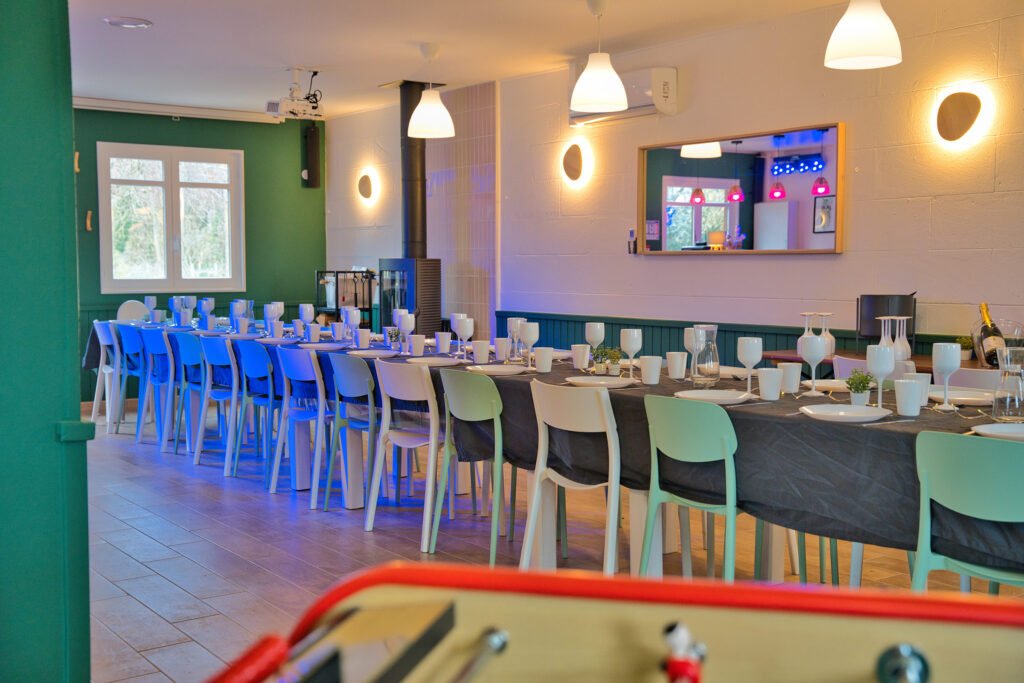 Salle de réception du gîte Ranch de Sologne avec grandes tables dressées pour les repas de groupe.