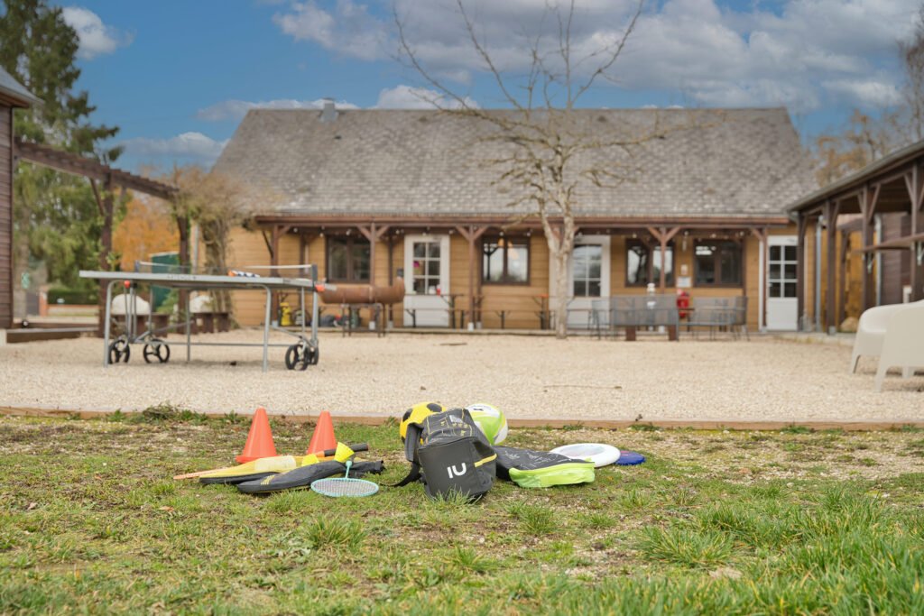 Extérieur du gîte Ranch de Sologne avec table de ping-pong et équipements de jeux en plein air, salle de réception en arrière-plan.