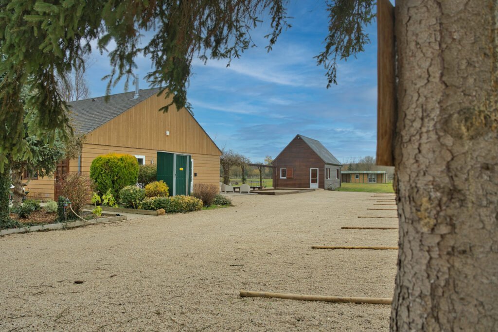 Entrée du gîte Ranch de Sologne avec parking à droite, salle de jeux en face et terrain de pétanque.
