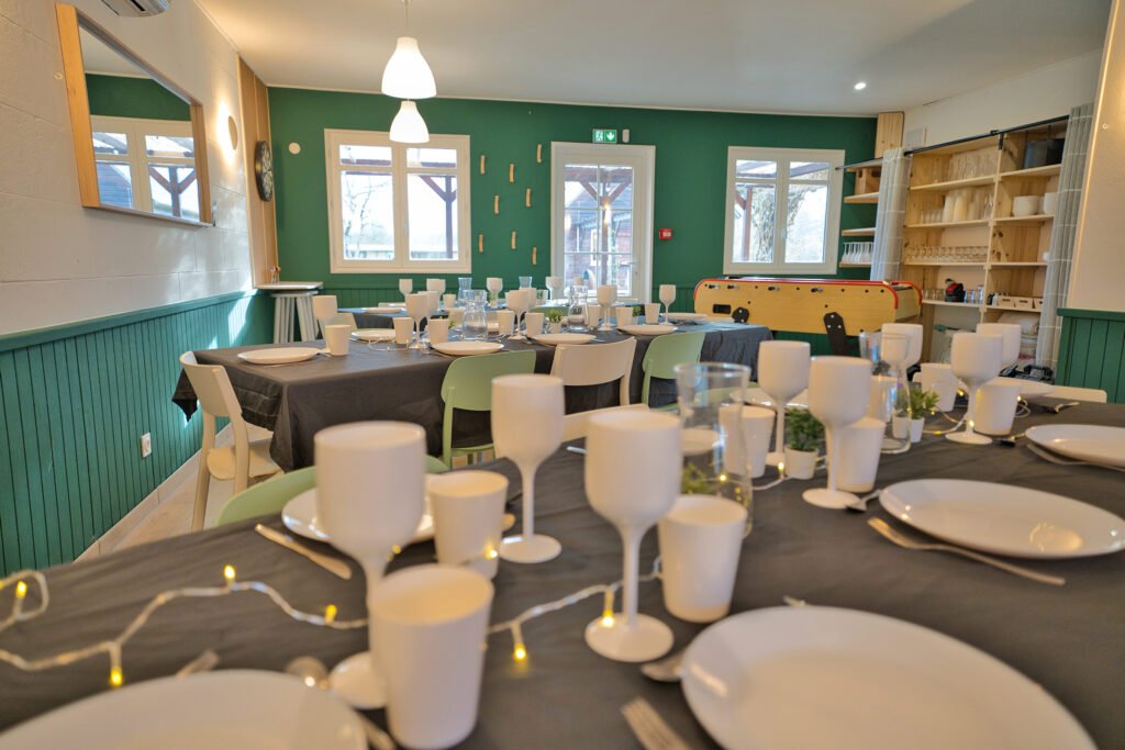Salle de réception du gîte Ranch de Sologne avec tables dressées, babyfoot et jeu de fléchettes.