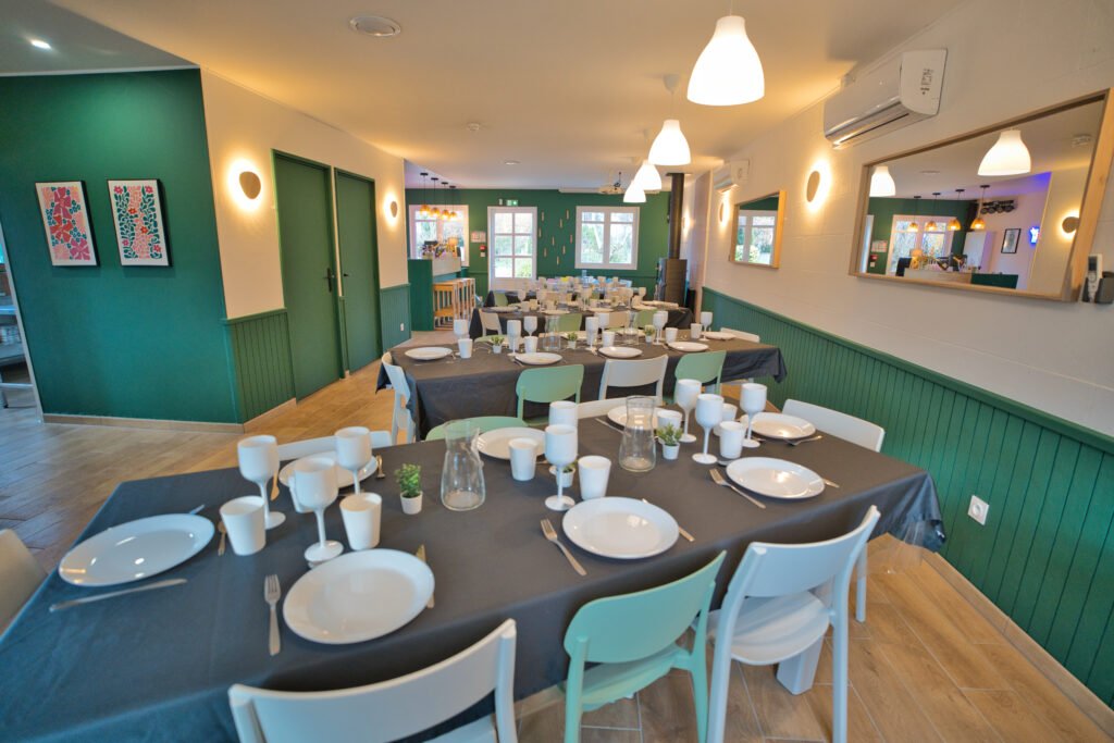 Salle de réception du gîte Ranch de Sologne avec grandes tables pour les repas de groupe.